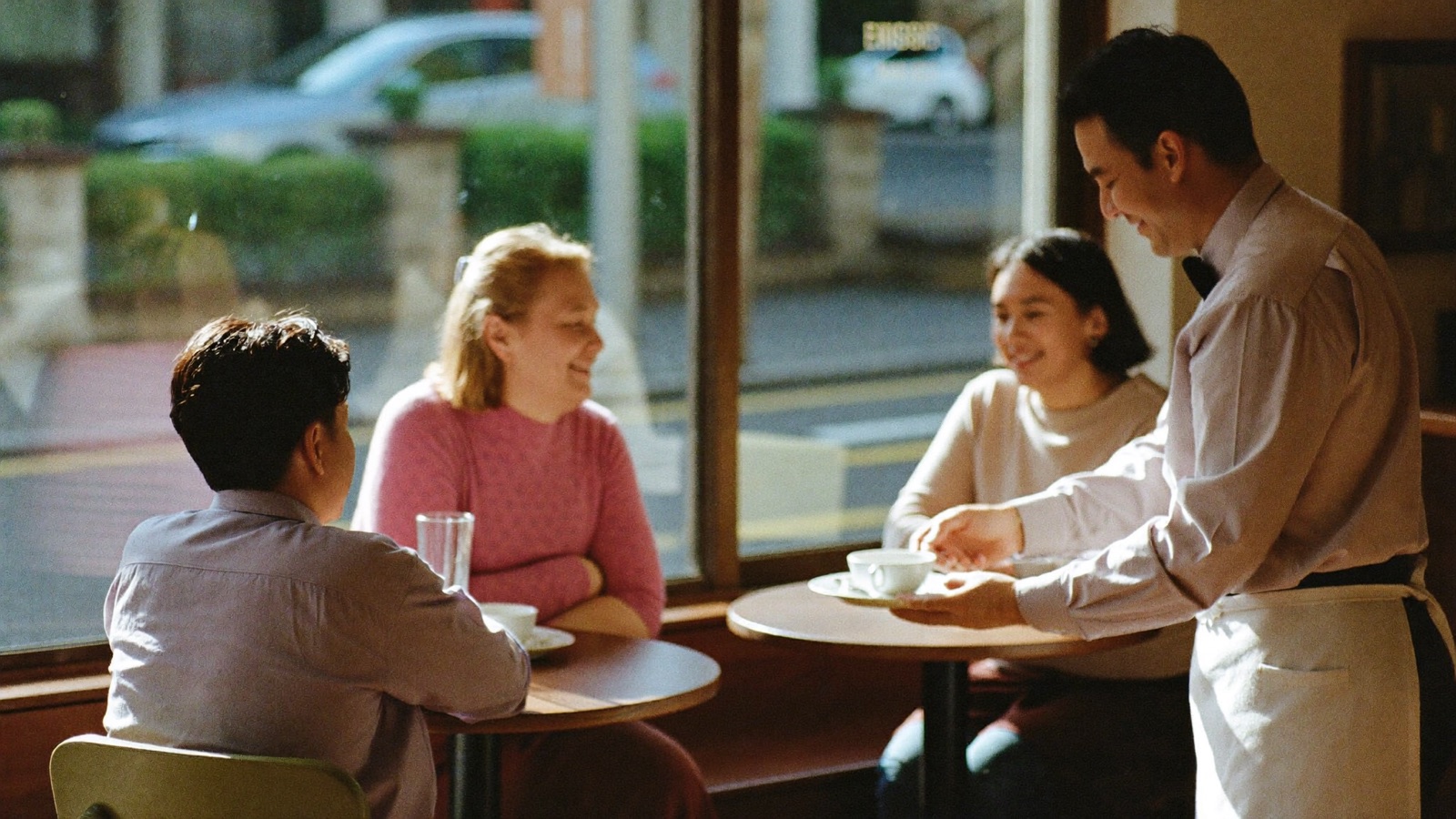 Waiter bringing coffees to regular customers at their usual table
